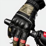 Gant de moto noir, vert et rouge tenant le frein d'une moto