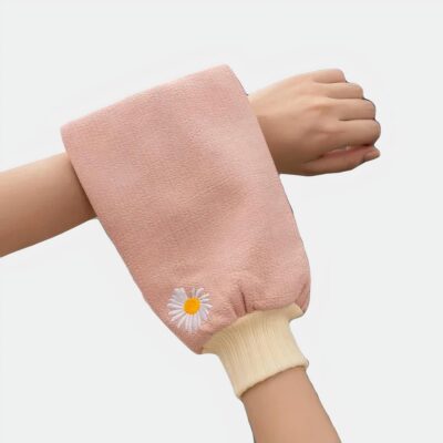 Gant de toilette rose avec une petite fleur utilisé par une personne.