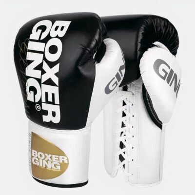 Photo de gants de boxe thaï noirs et blancs à lacets blancs à l'intérieur avec une large bande blanche au poignet avec marque dorée, le tout sur fond blanc