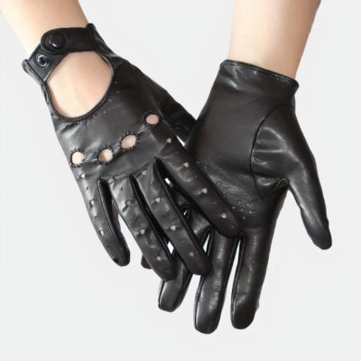 Photo de 2 mains de femme portant des gants de conduite en cuir noir l'un côté dos pour montrer les coutures, la fermeture par bouton pression et les trous d'aération et l'autre paume pour les trous d'aération, ils sont au dessus d'un magazine féminin