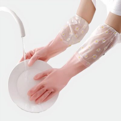 On voit une paire de mains gantées faire la vaisselle. les gants de ménage sont roses et transparents avec des fleurs.