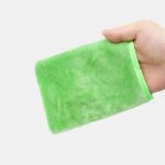 On voit une main qui manipule un gant démaquillant vert devant une coiffeuse