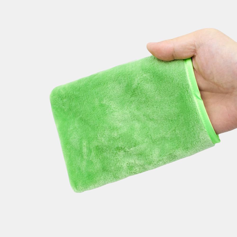 Gants démaquillants colorés pour femme On voit une main qui manipule un gant démaquillant vert devant une coiffeuse