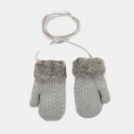 On voit des gants ficelle gris avec un petit ourson et un avion en motif en arrière plan