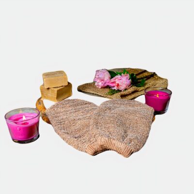 On voit un gant exfoliant en crin de cheval près de bougies et d'un nécessaire de cosmétiques pour SPA