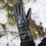 Photo d'un gant chauffant noir en PU et cuir avec bouton de commande marche/arrêt dans un pictogramme bleu sur le dessus de la main, sur un fond flouté de nature